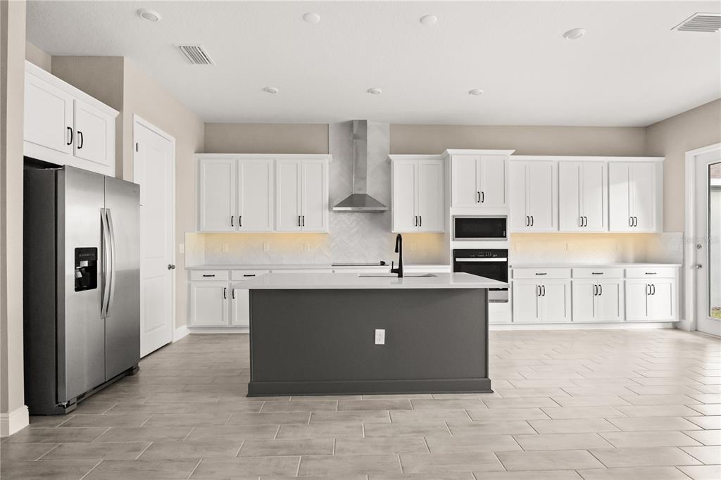 A modern kitchen features white cabinets, a dark gray island, and stainless steel appliances — 16848 HAMLIN VISTA ALLEY, WINTER GARDEN, FL