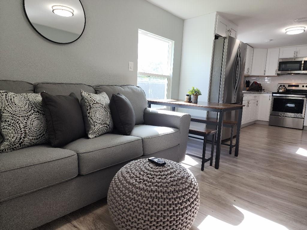 A living room with a gray sofa and a kitchen with white cabinets and appliances — 634 FOSTER AVENUE, WINTER GARDEN, FL