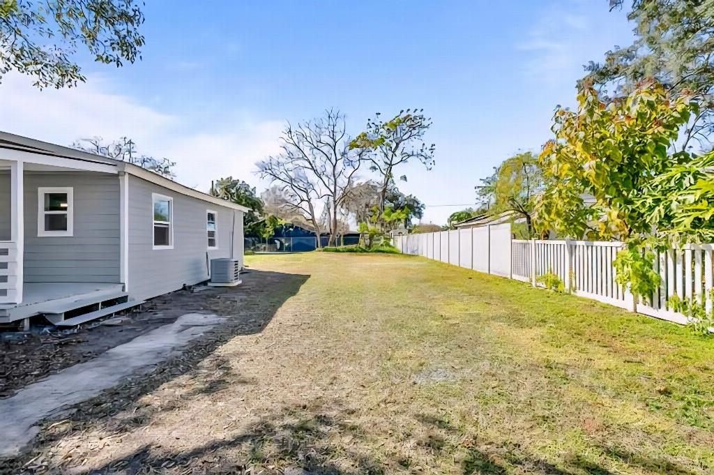 A side view of a light gray house with a yard and a white fence — 634 FOSTER AVENUE, WINTER GARDEN, FL