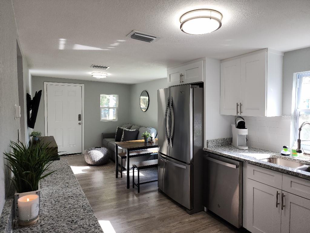 A kitchen with stainless steel appliances and granite countertops opens into a small living area — 634 FOSTER AVENUE, WINTER GARDEN, FL