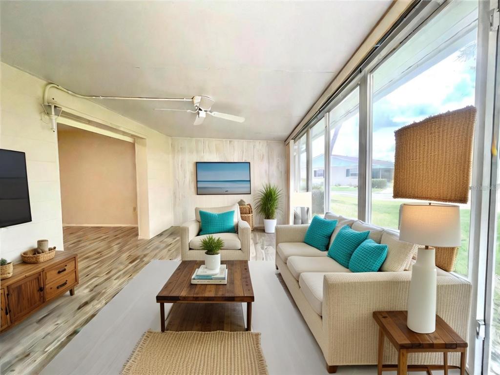 A sunroom features a beige sofa, armchair, wood coffee table, and large windows overlooking outdoors — 2687 GOLF COURSE DRIVE UNIT 219, SARASOTA, FL