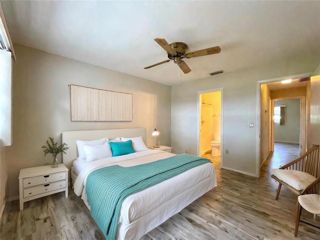 A bedroom features a bed with teal accents, a ceiling fan, and wood-look flooring — 2687 GOLF COURSE DRIVE UNIT 219, SARASOTA, FL