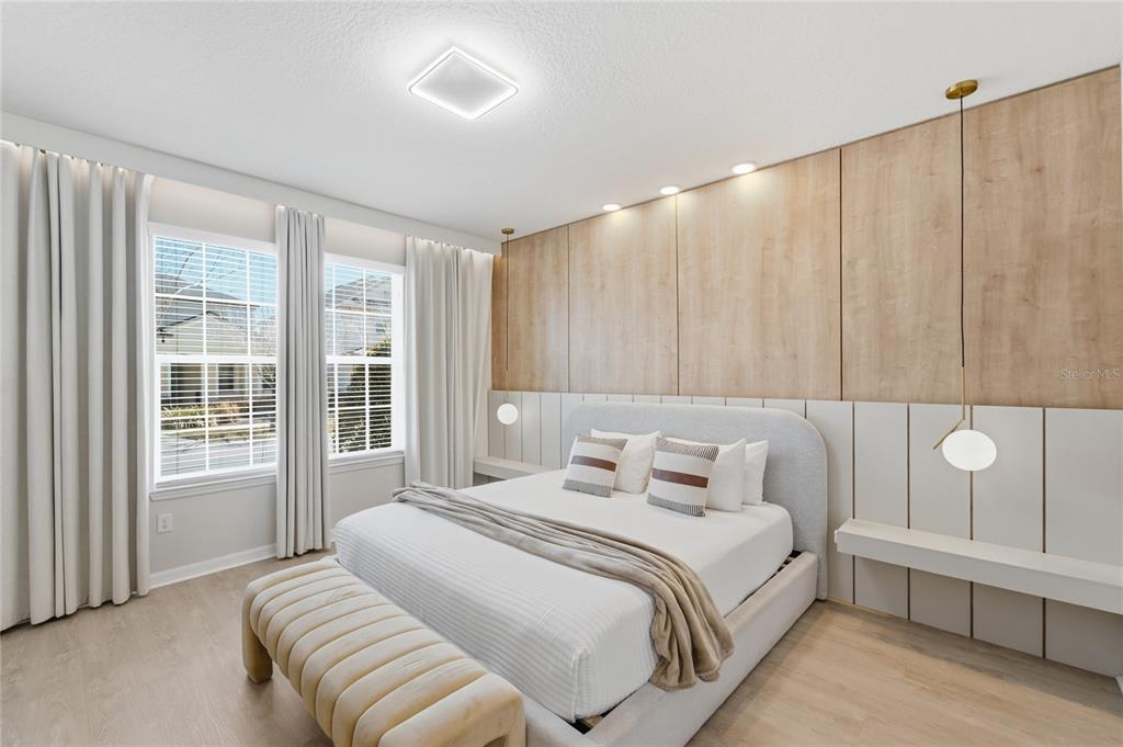 A modern bedroom features a light wood paneled accent wall, a gray bed, and pendant lighting — 1860 SAWYER PALM PLACE, KISSIMMEE, FL