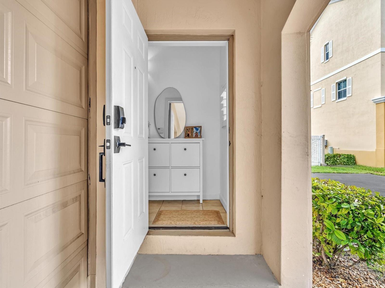 An open white front door reveals an entryway with a white shoe cabinet and mirror — 2329 Vintage Drive # 2329, Lighthouse Point FL 33064, LIGHTHOUSE POINT, FL