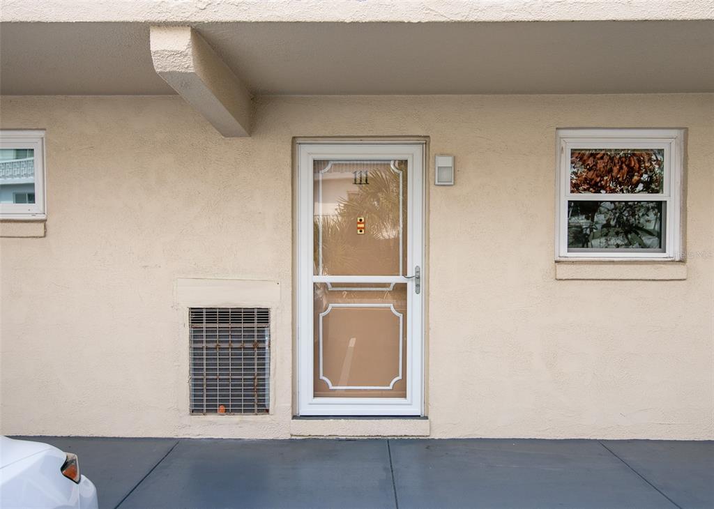 A beige exterior wall features a white storm door numbered 111, a window, and a vent — 2901 N HALIFAX AVENUE UNIT 111, DAYTONA BEACH, FL