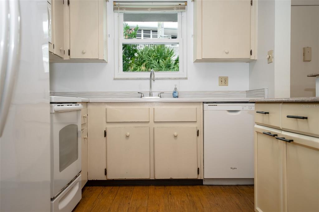 A kitchen features white cabinets, a sink under a window, and white appliances — 2901 N HALIFAX AVENUE UNIT 111, DAYTONA BEACH, FL