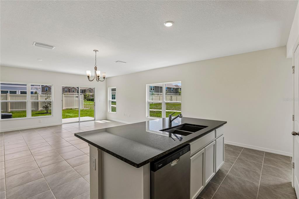 A kitchen island with a dark countertop sits in an open-concept room with tile flooring — 679 MEADOWS EDGE PLACE, LAKE WALES, FL