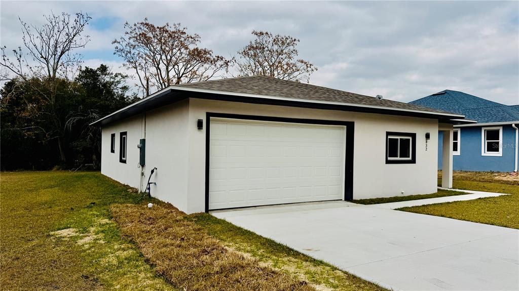 A white detached garage with a black trim and a concrete driveway sits on grass — 832 E DESOTO STREET, CLERMONT, FL