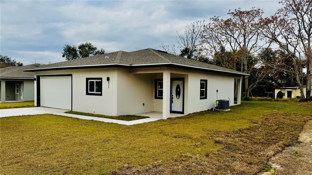 A single-story house with a white exterior, a garage, and a covered front entryway — 832 E DESOTO STREET, CLERMONT, FL
