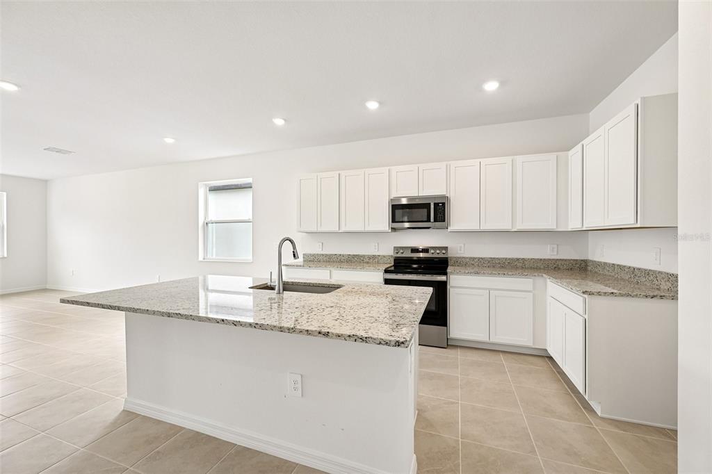 A kitchen with white cabinets, granite countertops, a center island, and stainless steel appliances — 4422 OUTHAUL RUN, PALMETTO, FL
