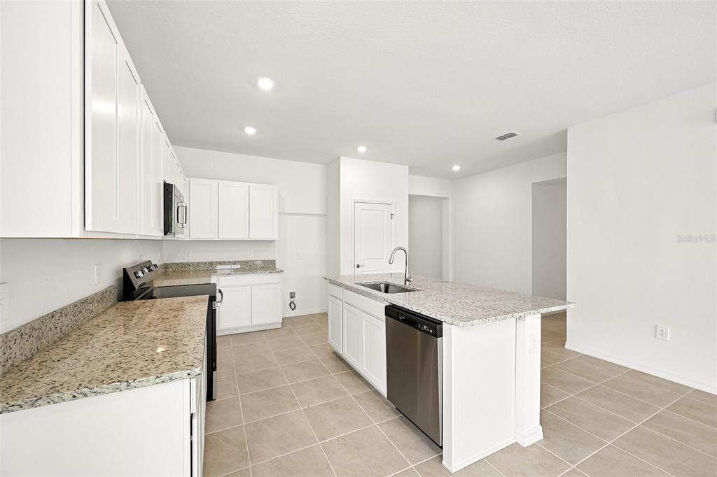 A kitchen with white cabinets, granite countertops, a stainless steel dishwasher, and tile flooring — 4422 OUTHAUL RUN, PALMETTO, FL