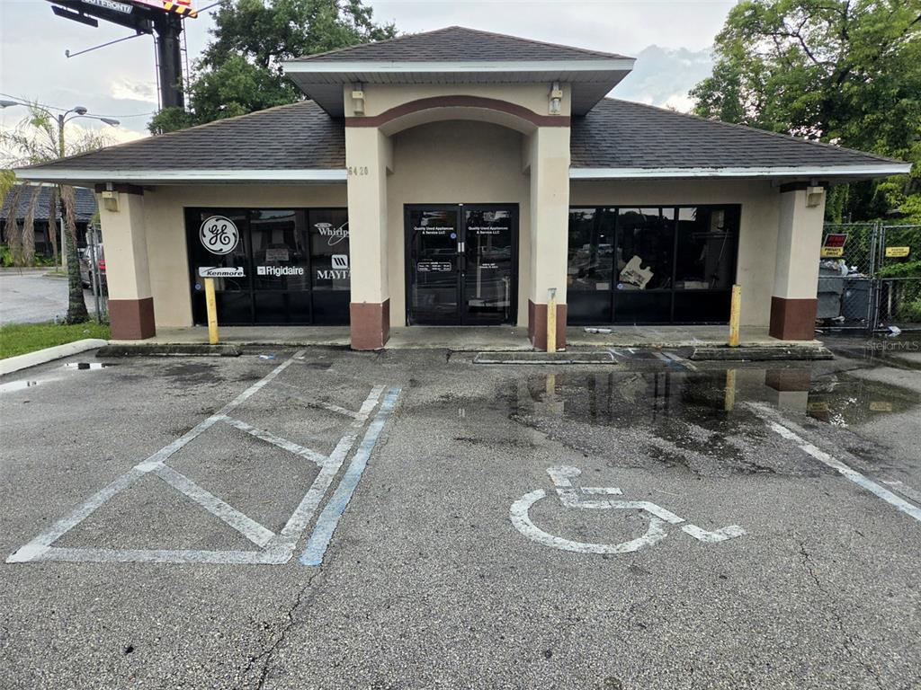 A single-story commercial building with a central entrance and a paved parking lot in front — 6420 N ORANGE BLOSSOM TRAIL, ORLANDO, FL