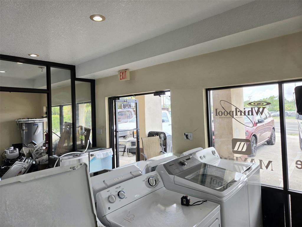 A retail showroom displays several white washing machines near large glass windows and an exit door — 6420 N ORANGE BLOSSOM TRAIL, ORLANDO, FL