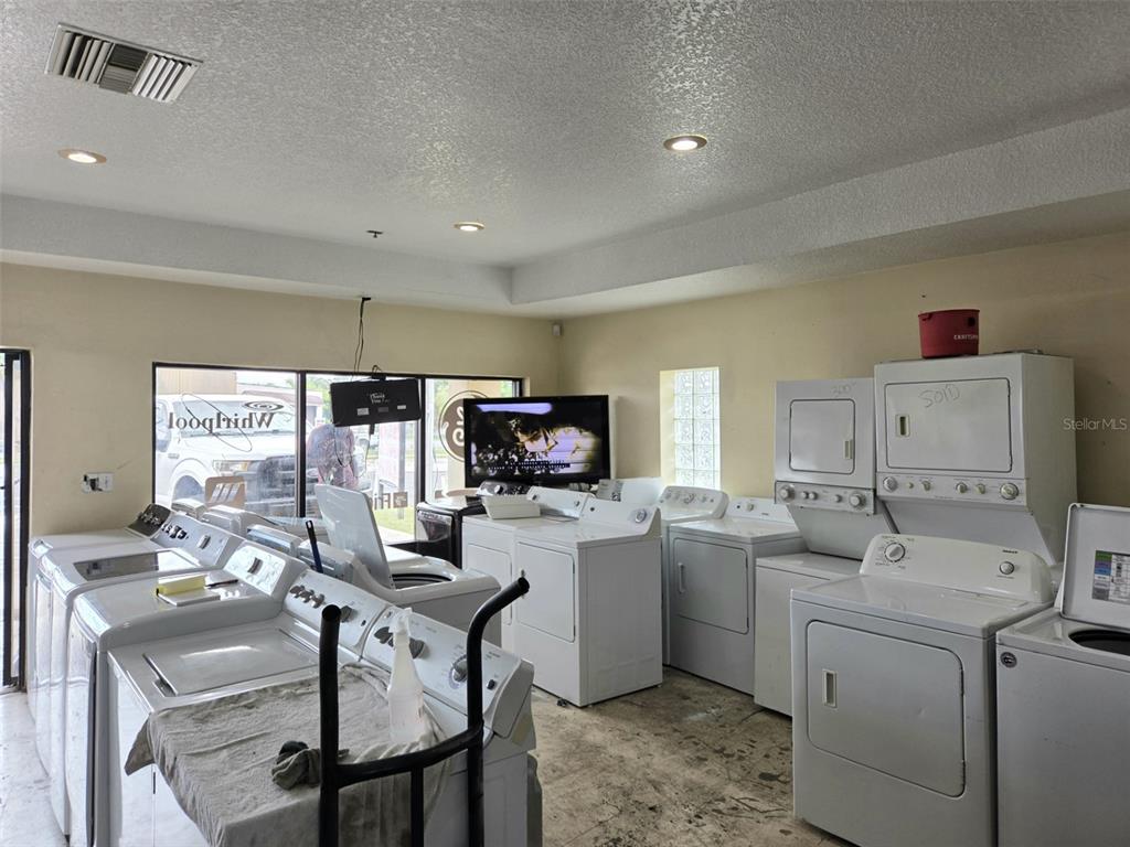 A room filled with various white washing machines and dryers arranged on a concrete floor — 6420 N ORANGE BLOSSOM TRAIL, ORLANDO, FL