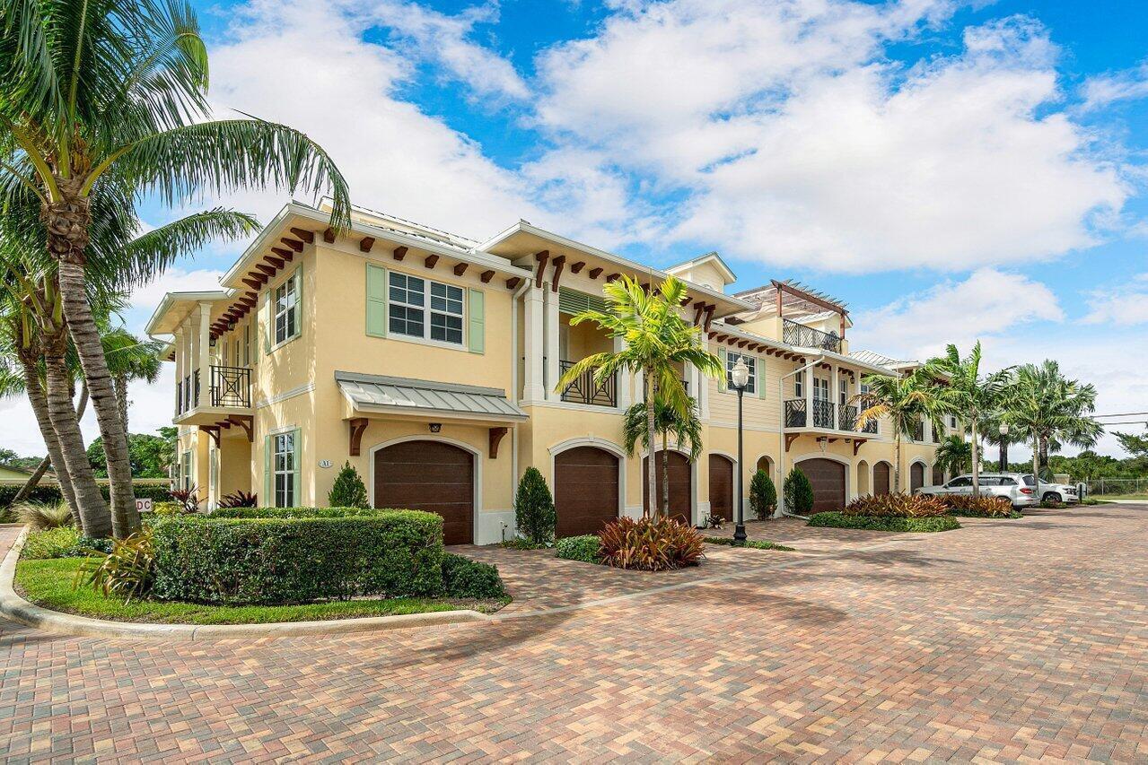 A multi-story yellow building with a brick driveway, palm trees, and multiple garage bays — 3770 County Line Road # C1, Tequesta FL 33469, TEQUESTA, FL