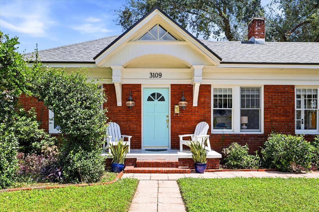 A brick house exterior features a light blue front door, white chairs, and potted plants — 3109 W SAN CARLOS STREET, TAMPA, FL