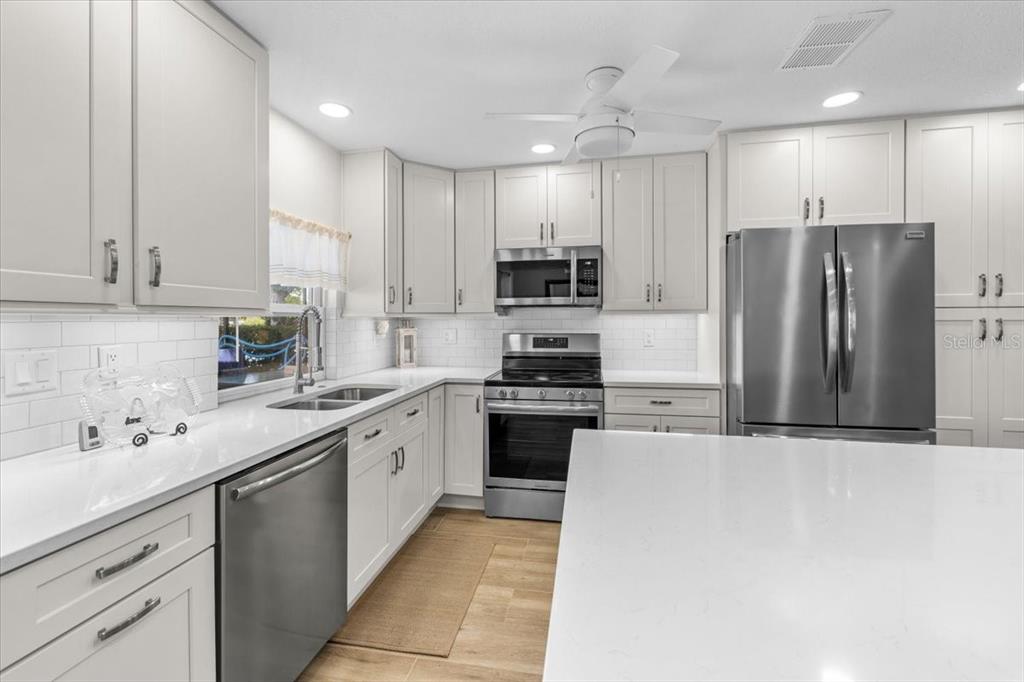 A modern kitchen features white cabinets, stainless steel appliances, and a large white island — 4267 CARLOS COURT, HERNANDO BEACH, FL