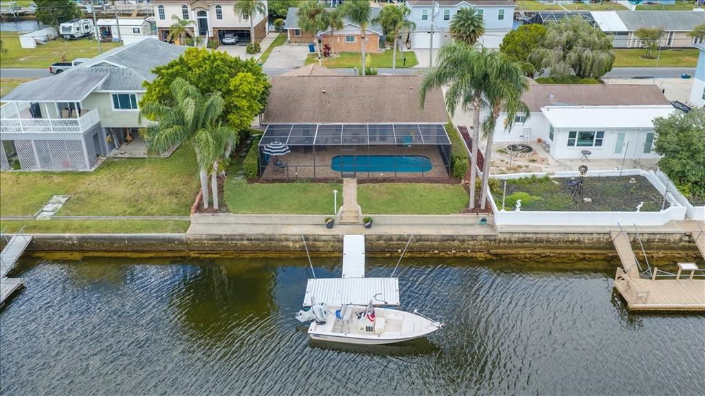An aerial view shows a waterfront house with a pool, screened enclosure, and private dock — 4267 CARLOS COURT, HERNANDO BEACH, FL
