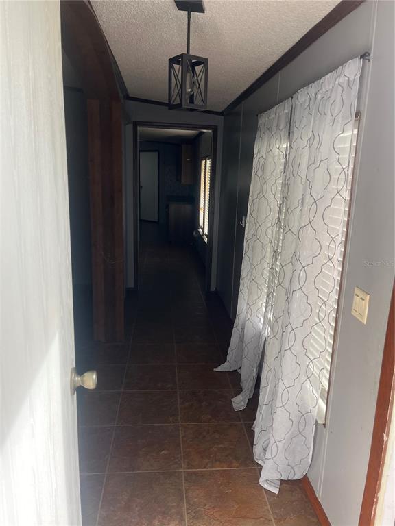 A hallway with tiled flooring leads to a doorway under a hanging lantern light fixture — 1145 YAUN ROAD, MOORE HAVEN, FL