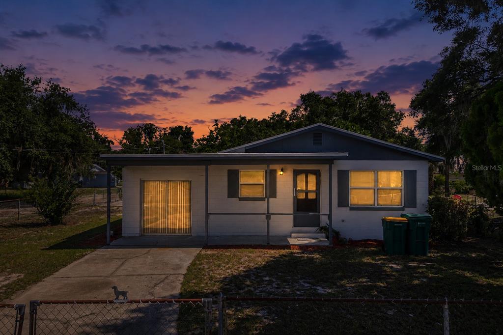A single-story house with a covered porch and driveway at dusk — 922 BATES AVENUE, EUSTIS, FL