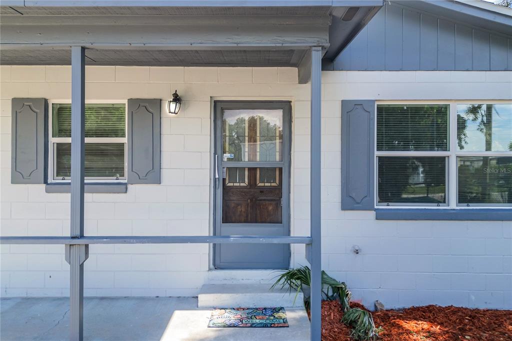 A front porch with a gray screen door and white concrete block walls — 922 BATES AVENUE, EUSTIS, FL
