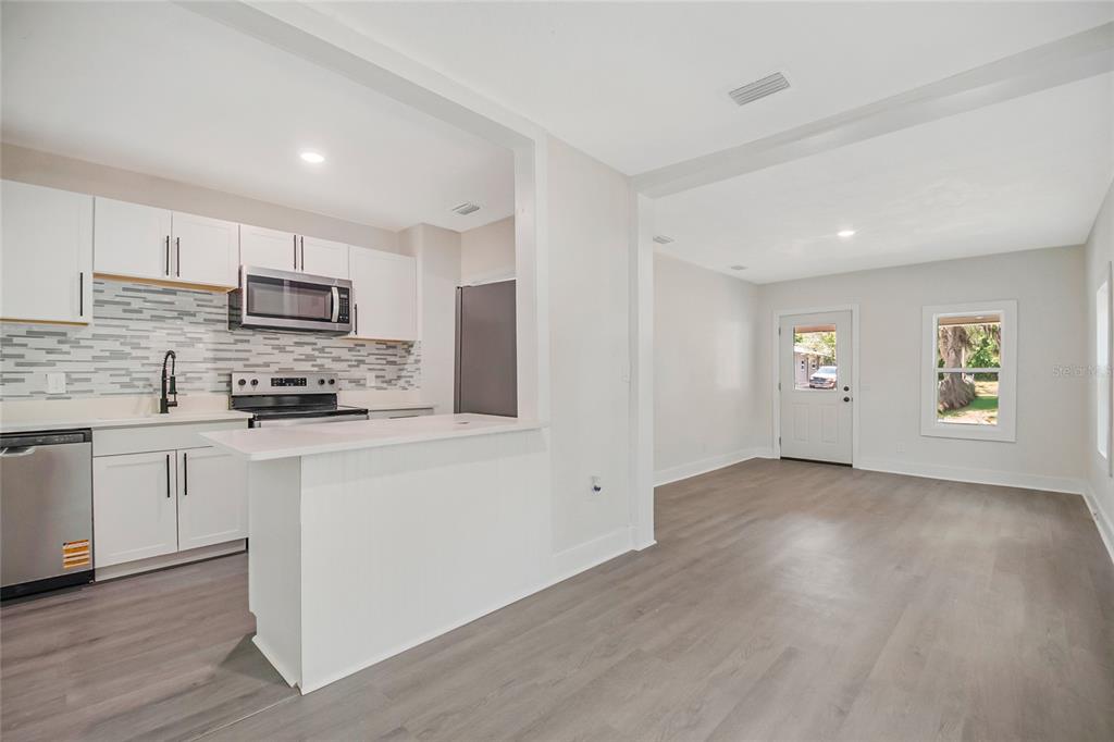 A kitchen with white cabinets and a breakfast bar opens into a living area — 922 BATES AVENUE, EUSTIS, FL