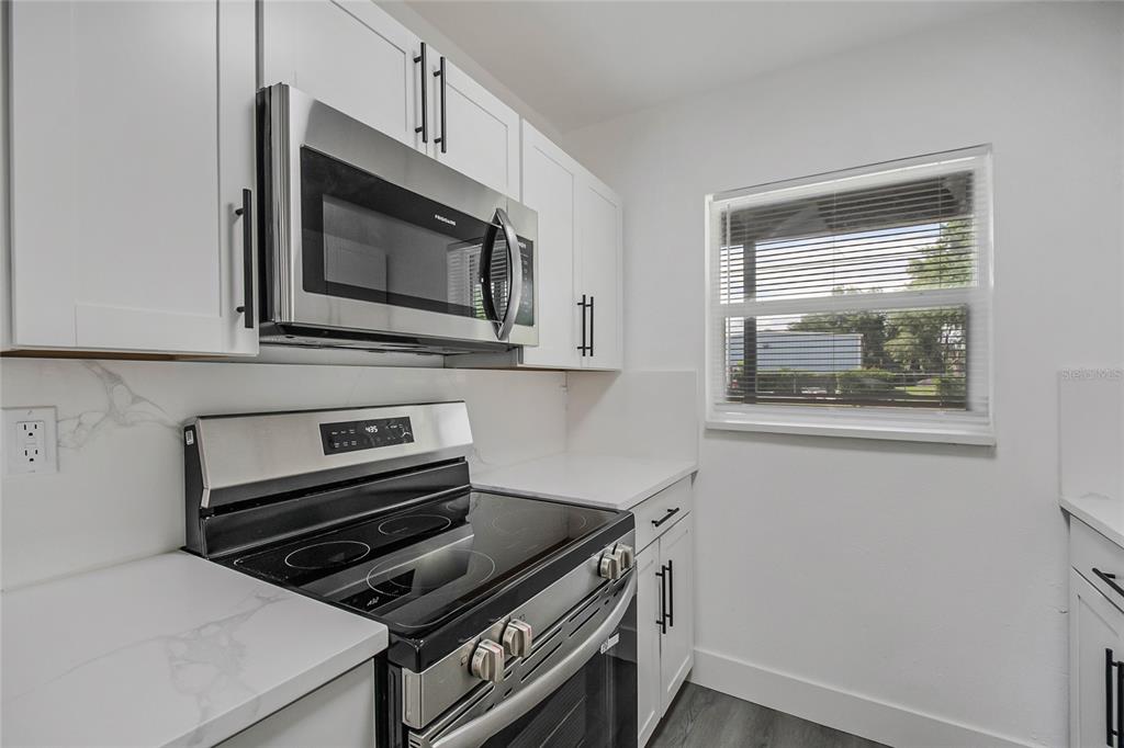 A kitchen features white cabinets, stainless steel appliances, and a window with blinds — 922 BATES AVENUE, EUSTIS, FL