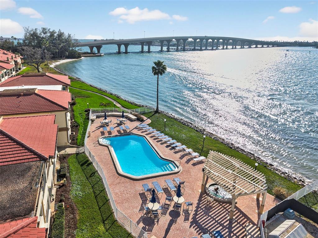 An aerial view shows a swimming pool and patio area beside a large bridge — 6210 SUN BOULEVARD UNIT 112, ST PETERSBURG, FL