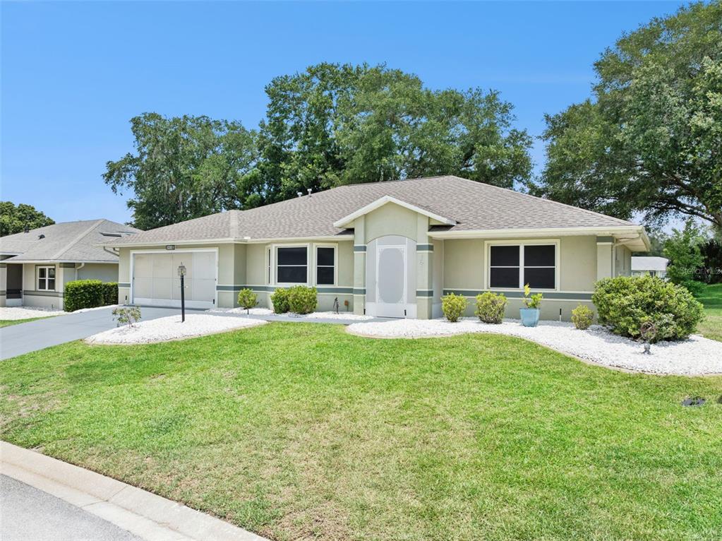 A single-story house with a light green exterior, a two-car garage, and a grassy lawn — 6419 BORG STREET, LEESBURG, FL