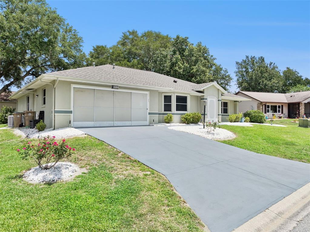 A single-story house with a gray driveway, a garage, and a light-colored stucco exterior — 6419 BORG STREET, LEESBURG, FL