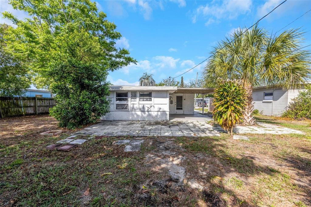 The exterior of a single-story house features a concrete patio, a carport, and palm trees — 4040 FLAMINGO DRIVE, NEW PORT RICHEY, FL