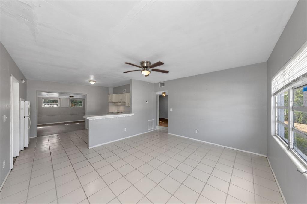 A bright, open-concept living and dining area features light gray walls and white tile flooring — 4040 FLAMINGO DRIVE, NEW PORT RICHEY, FL