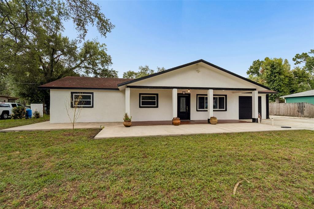 A single-story house with a white stucco exterior, black trim, and a covered front porch — 5712 20TH AVENUE S, TAMPA, FL