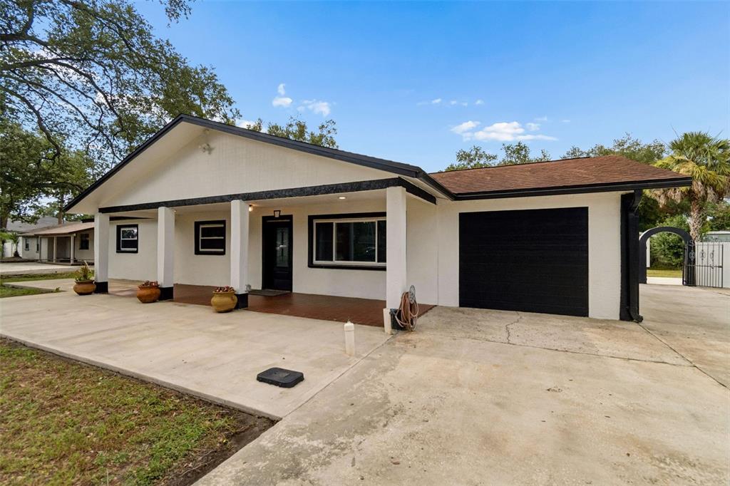 A single-story house with a white exterior, black trim, a covered porch, and a garage — 5712 20TH AVENUE S, TAMPA, FL
