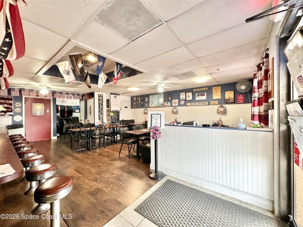 A restaurant interior features a bar with stools, dining tables, and patriotic wall decor — 722 WEST AVENUE, COCOA, FL