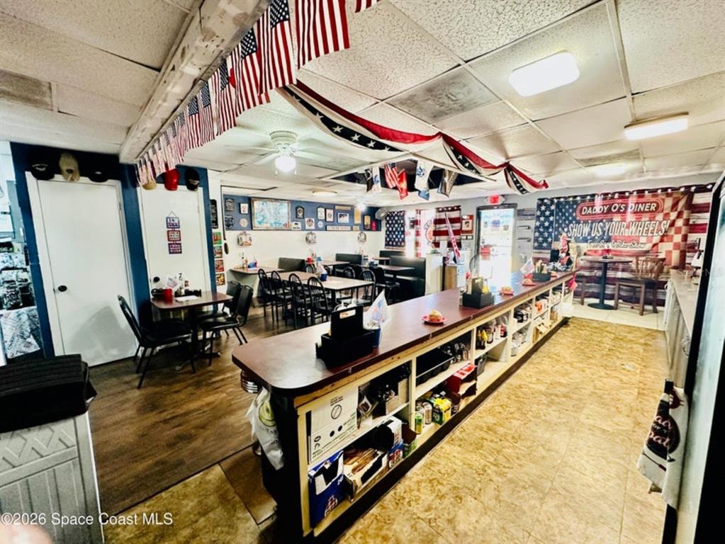 This diner interior features a long service counter, tables, chairs, and patriotic flag decorations — 722 WEST AVENUE, COCOA, FL