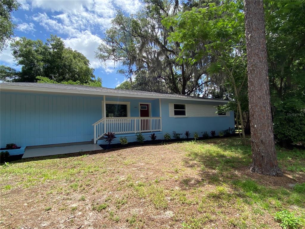 A light blue single-story house with a front porch and a red door — 1411 SE 35TH ST, GAINESVILLE, FL