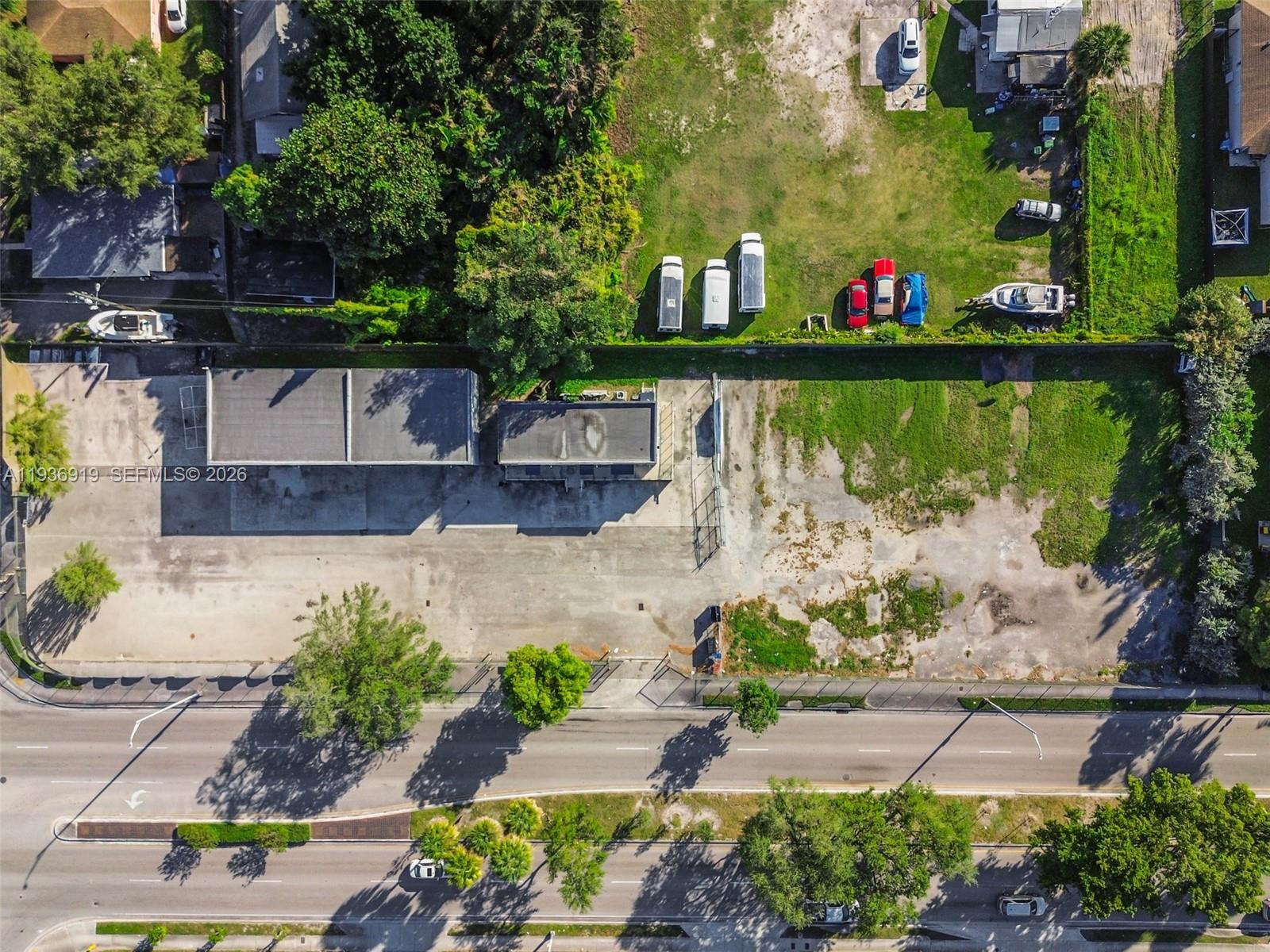An aerial view shows a commercial building with a large paved lot and adjacent grass — 3130 NW 62nd St, Miami FL 33147, MIAMI, FL