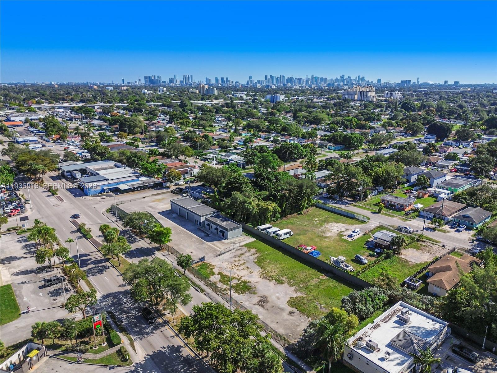 An aerial view shows a commercial lot with a building and parking near a city — 3130 NW 62nd St, Miami FL 33147, MIAMI, FL