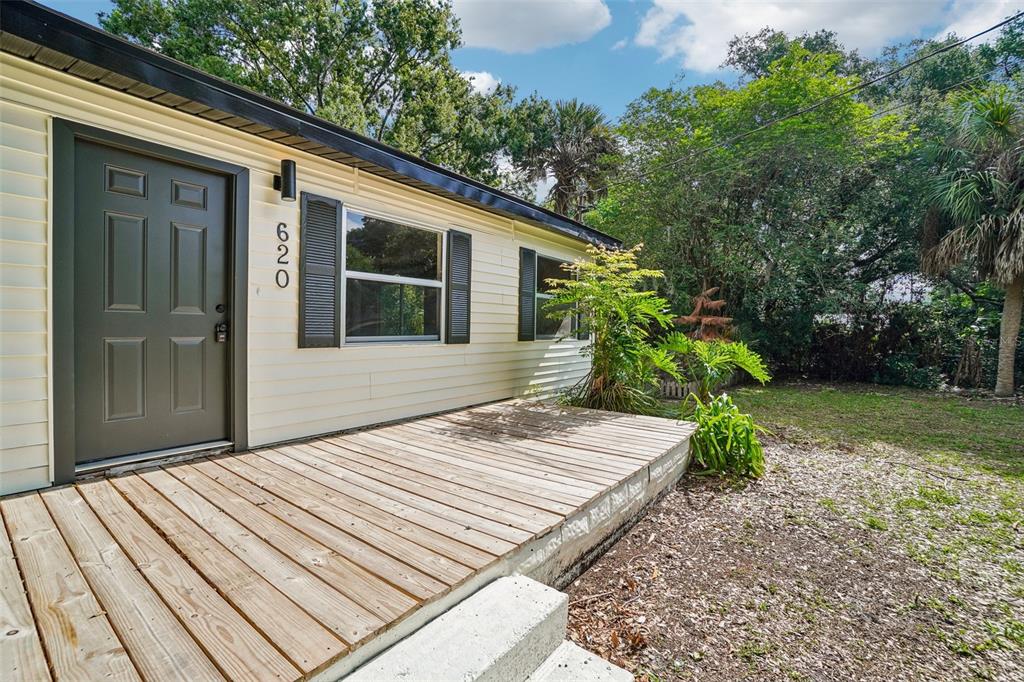 A light-colored house exterior features a wooden deck, a dark door, and black shutters — 620 2ND STREET, POLK CITY, FL