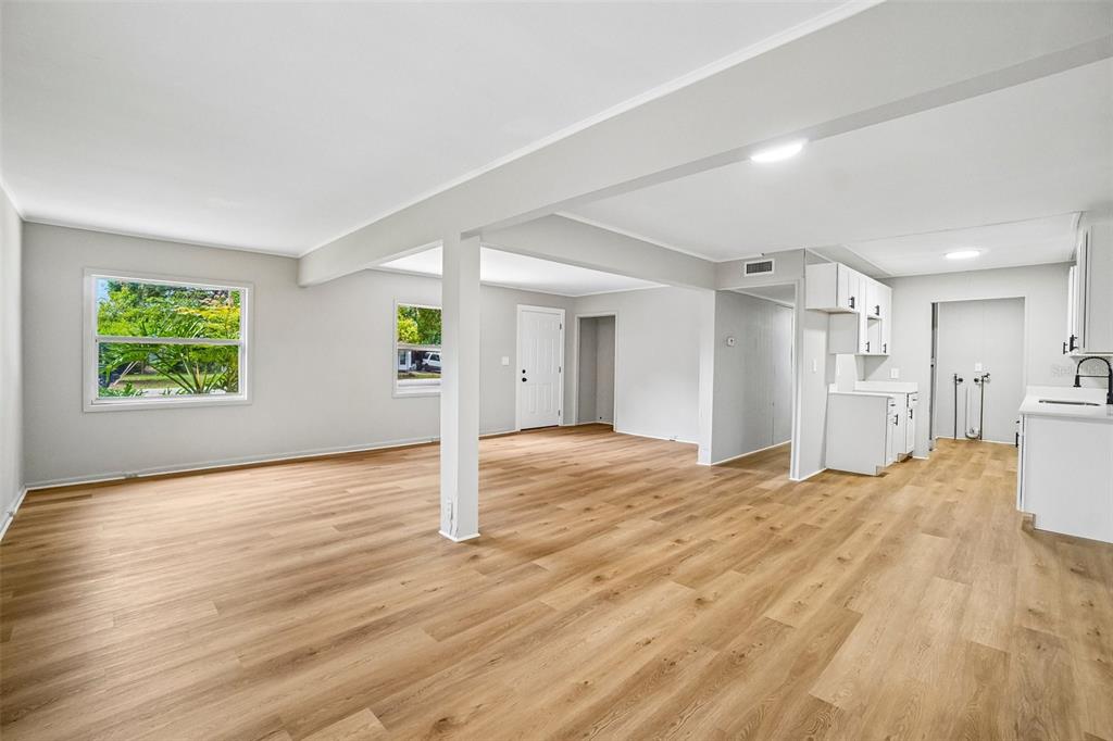 An open-concept living and kitchen area features light wood-look flooring and white walls — 620 2ND STREET, POLK CITY, FL