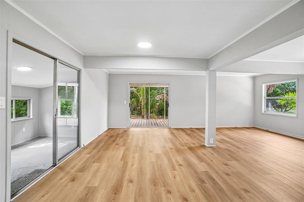An empty room with light wood-look flooring, a sliding glass door, and a support column — 620 2ND STREET, POLK CITY, FL
