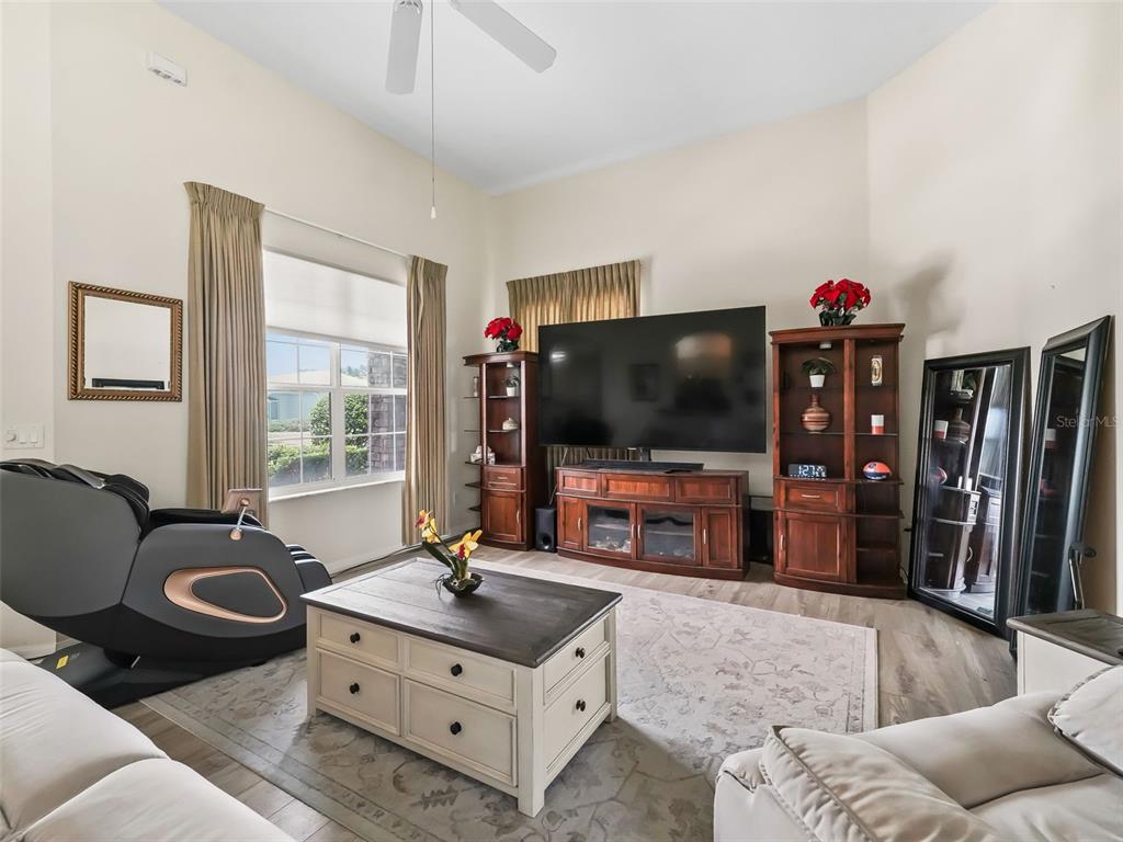 A living room features a large television, wooden media console, coffee table, and massage chair — 17435 SE 112TH AVENUE, SUMMERFIELD, FL