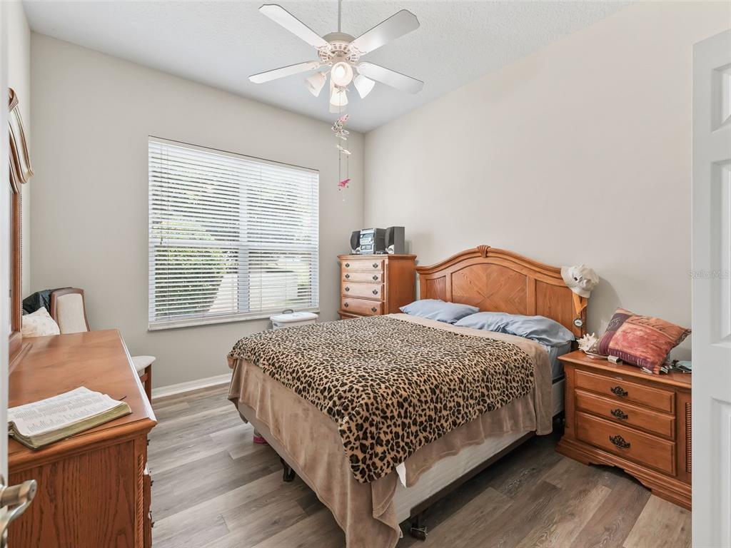 A bedroom features a leopard-print bedspread, wooden furniture, a ceiling fan, and light-colored walls — 17435 SE 112TH AVENUE, SUMMERFIELD, FL