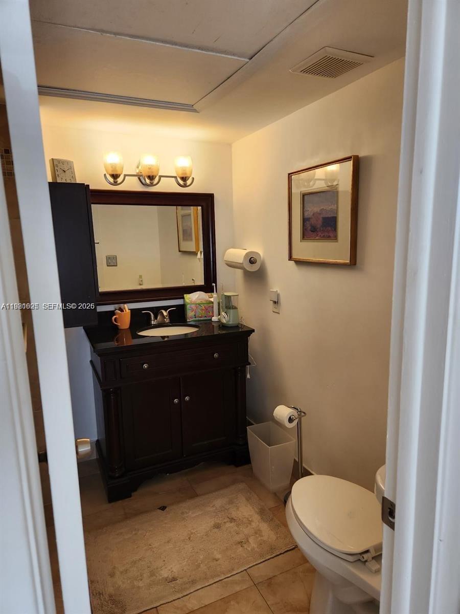 A bathroom features a dark wood vanity, a framed mirror, and a toilet — 9 NE 19th Ct # 208C, Wilton Manors FL 33305, WILTON MANORS, FL