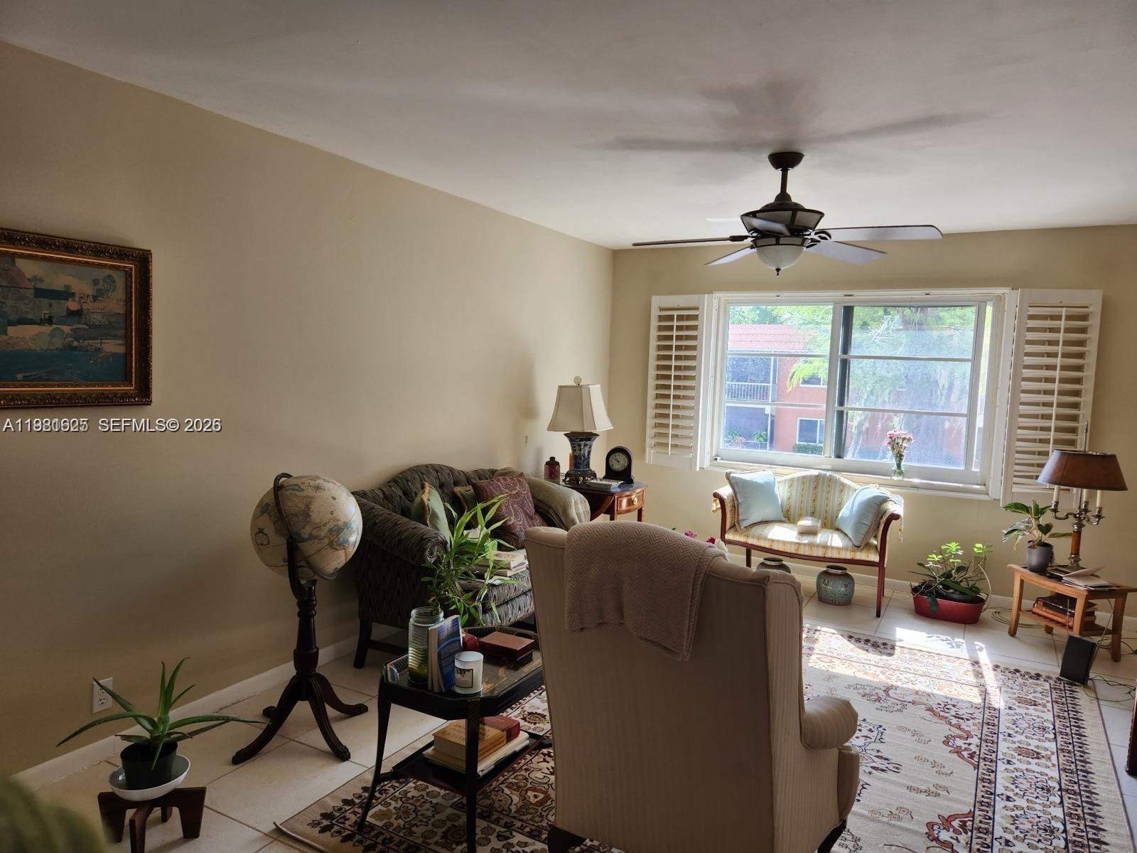 A living room features a ceiling fan, a patterned area rug, and a window with shutters — 9 NE 19th Ct # 208C, Wilton Manors FL 33305, WILTON MANORS, FL