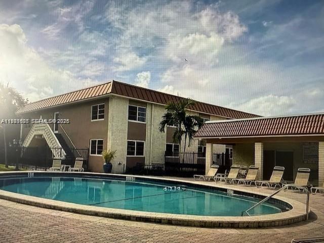 A two-story apartment building features a swimming pool and lounge chairs on the patio — 9 NE 19th Ct # 208C, Wilton Manors FL 33305, WILTON MANORS, FL
