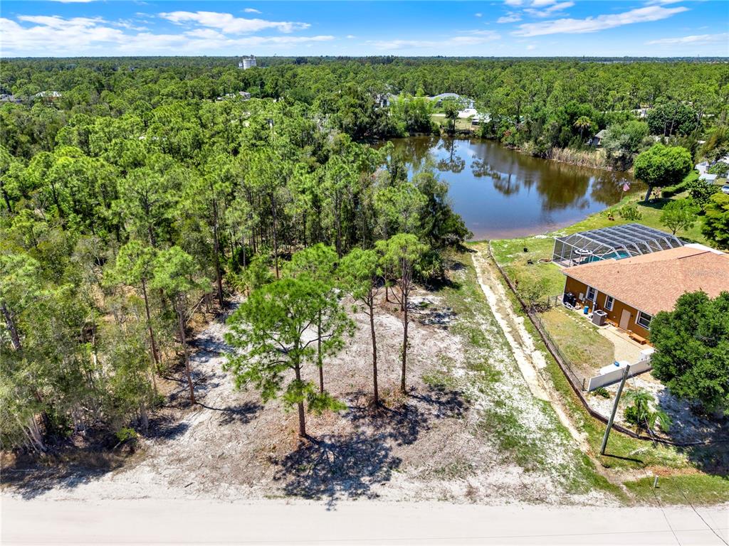 An aerial view shows a vacant, wooded lot next to a house with a pool — 12277 FINWICK DRIVE, PUNTA GORDA, FL