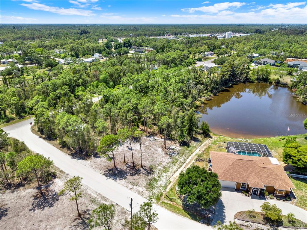 An aerial view shows a vacant lot next to a house with a pool — 12277 FINWICK DRIVE, PUNTA GORDA, FL
