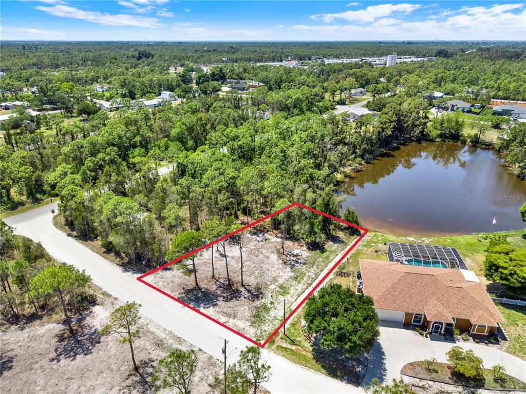 An aerial view shows a vacant, rectangular lot outlined in red next to a pond — 12277 FINWICK DRIVE, PUNTA GORDA, FL